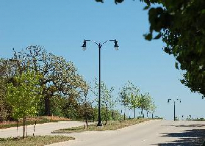 A four line city street with a divided median and street lights in the center.
